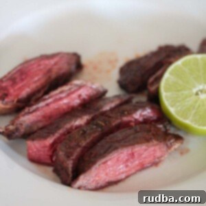 Perfect Air Fryer Carne Asada 2 air fryer carne asada on a white plate with lime on the side.