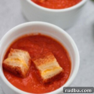 Lush Tomato Basil Bisque 2 Two small bowls of creamy tomato soup with grilled cheese croutons on top.