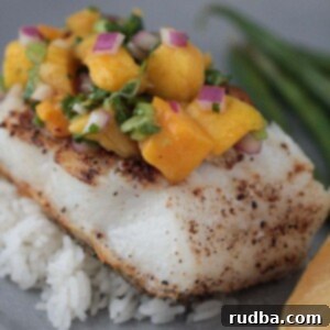 Bright Mango Chilean Sea Bass 2 Chilean sea bass with mango salsa and rice on a plate.