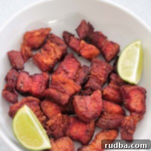 Air Fryer Pork Belly Perfection 2 air fryer pork belly in a white plate with two lime wedges.