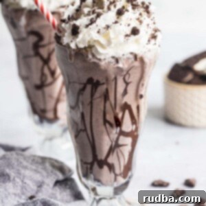 Oreo cookie milkshake with whipped cream and a red and white straw.