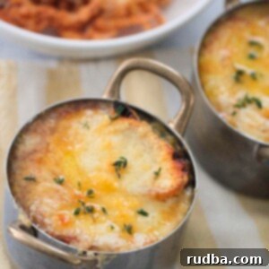 French onions soup with melted cheese and fresh thyme on top.