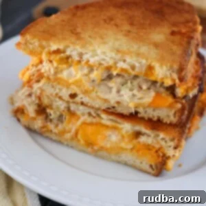Quick and Crispy Air Fryer Tuna Melt 2 air fryer tuna melt sandwiches on a white plate.