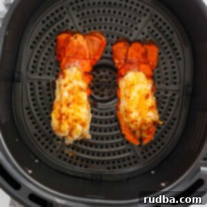 Two cooked lobster tails in the air fryer basket.