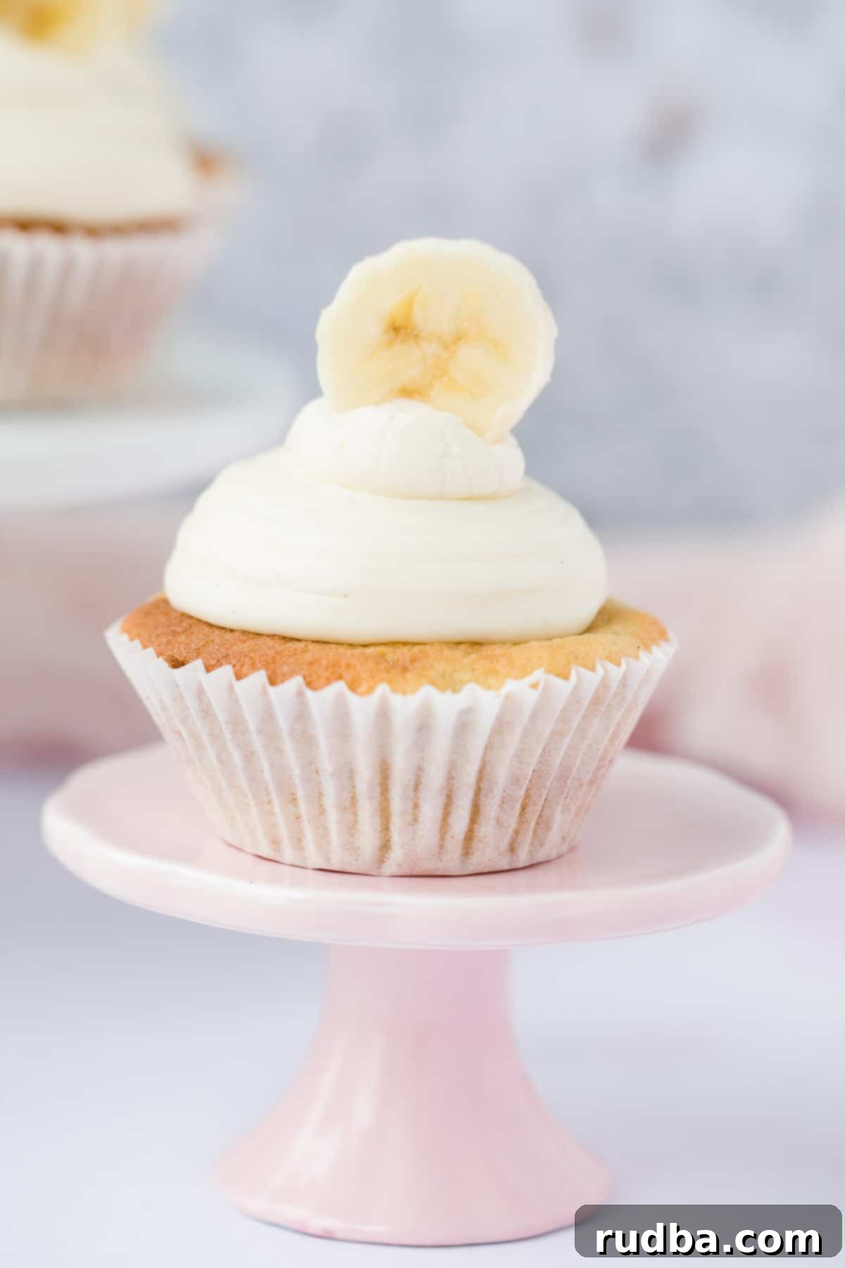 one banana cupcake on a small pink cake stand.