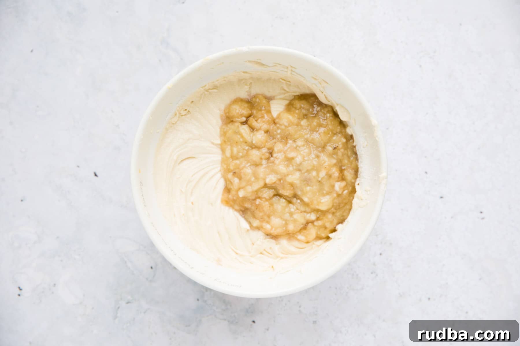 pureed banana and cake batter in a white bowl.