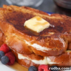 Indulgent Stuffed French Toast 2 Two stuffed French toasts with butter, syrup, and berries.