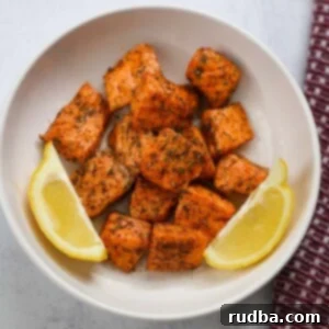 Crispy Air Fryer Salmon Bites 2 air fryer salmon bites with lemon wedges.