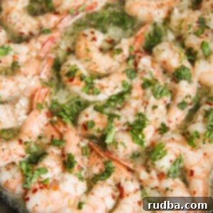 Irresistible Shrimp Creations 12 Baked shrimp with parsley in a cast iron skillet up close.