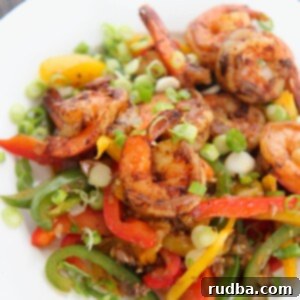 Irresistible Shrimp Creations 15 Jerk shrimp with peppers and onions on a white plate.