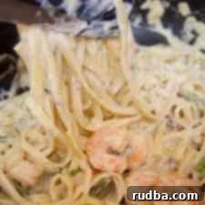 Irresistible Shrimp Creations 20 Garlic Shrimp Fettuccine Alfredo served with fresh herbs.