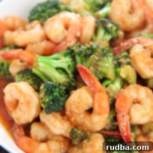Irresistible Shrimp Creations 21 Shrimp and broccoli with sauce in a white plate.