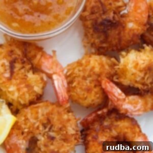 Irresistible Shrimp Creations 4 Six fried coconut shrimp with orange sauce and lemon wedges on the side.