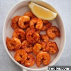 Irresistible Shrimp Creations 7 Air fryer honey chipotle shrimp in a white dish with a lemon wedge on the side.