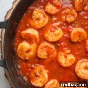 Irresistible Shrimp Creations 8 Cuban shrimp creole (enchilado de camarones) with red sauce in a black skillet up close.