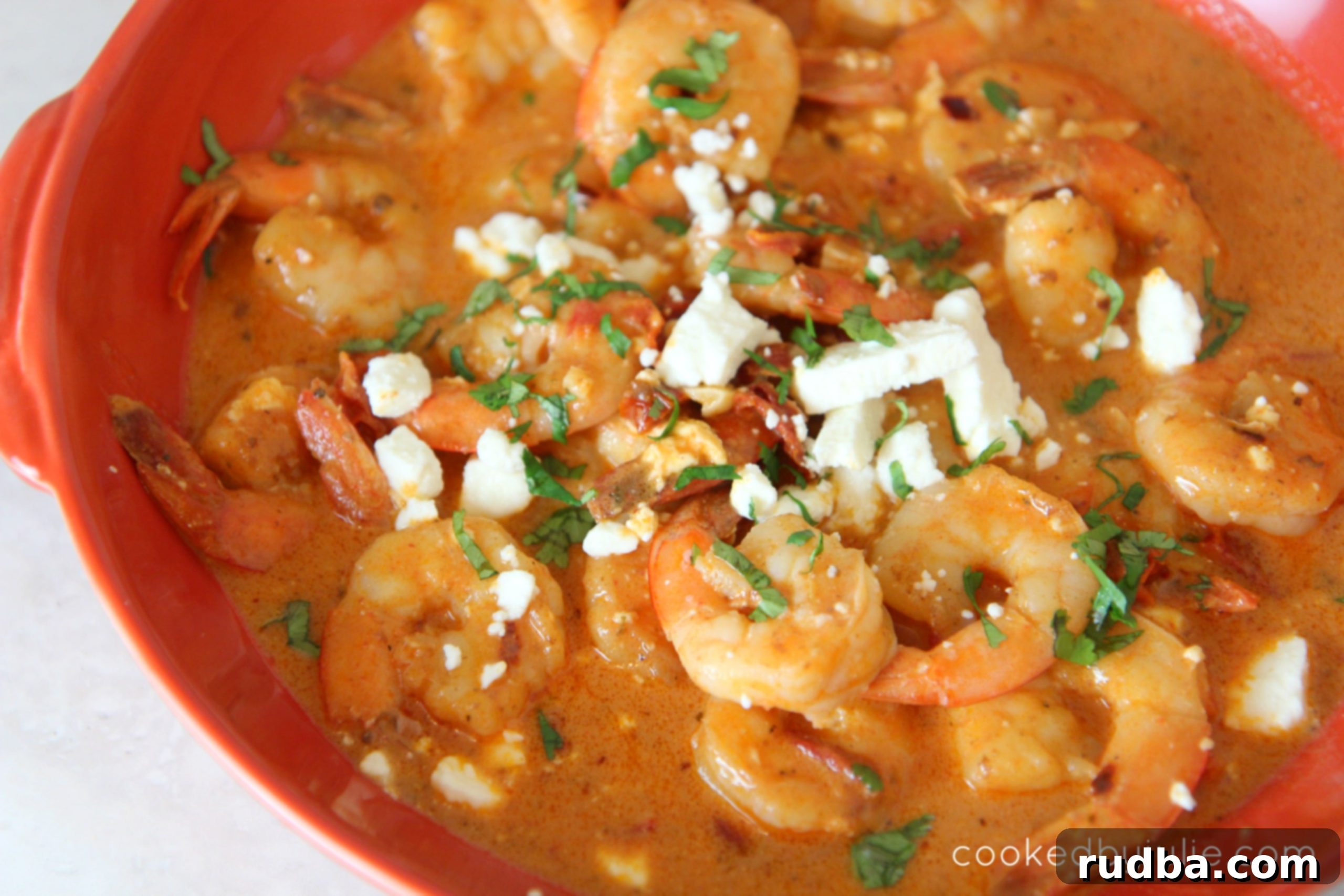 A bowl of creamy saucy shrimp garnished with fresh parsley.