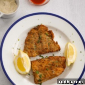 air fryer grouper fillets with lemon wedges, tartar sauce, and hot sauce.