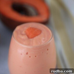 Batido de Mamey, a creamy Cuban tropical milkshake, in a glass with a piece of fruit on top.