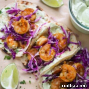 Air Fryer Shrimp Taco Feast 2 Three air fryer shrimp tacos with limes and avocado crema on the side.