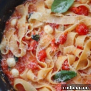 cherry tomato pasta with basil and cheese on top.
