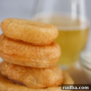four beer battered onion rings with a glass of beer in the background.