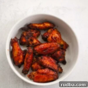Crispy Air Fryer Honey BBQ Wings 2 Air fryer honey bbq wings on a white plate with a sprig of rosemary.