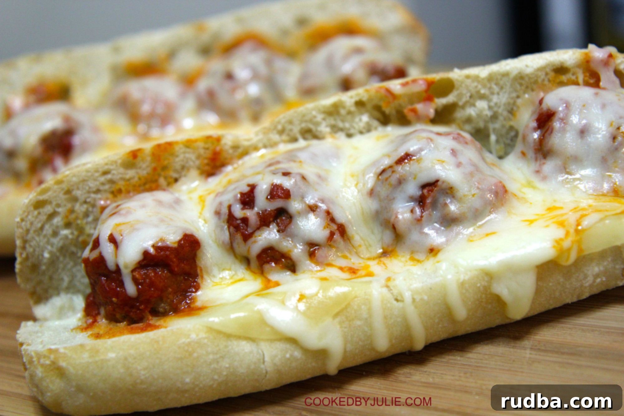 two meatball parmesan sandwich on a wooden board