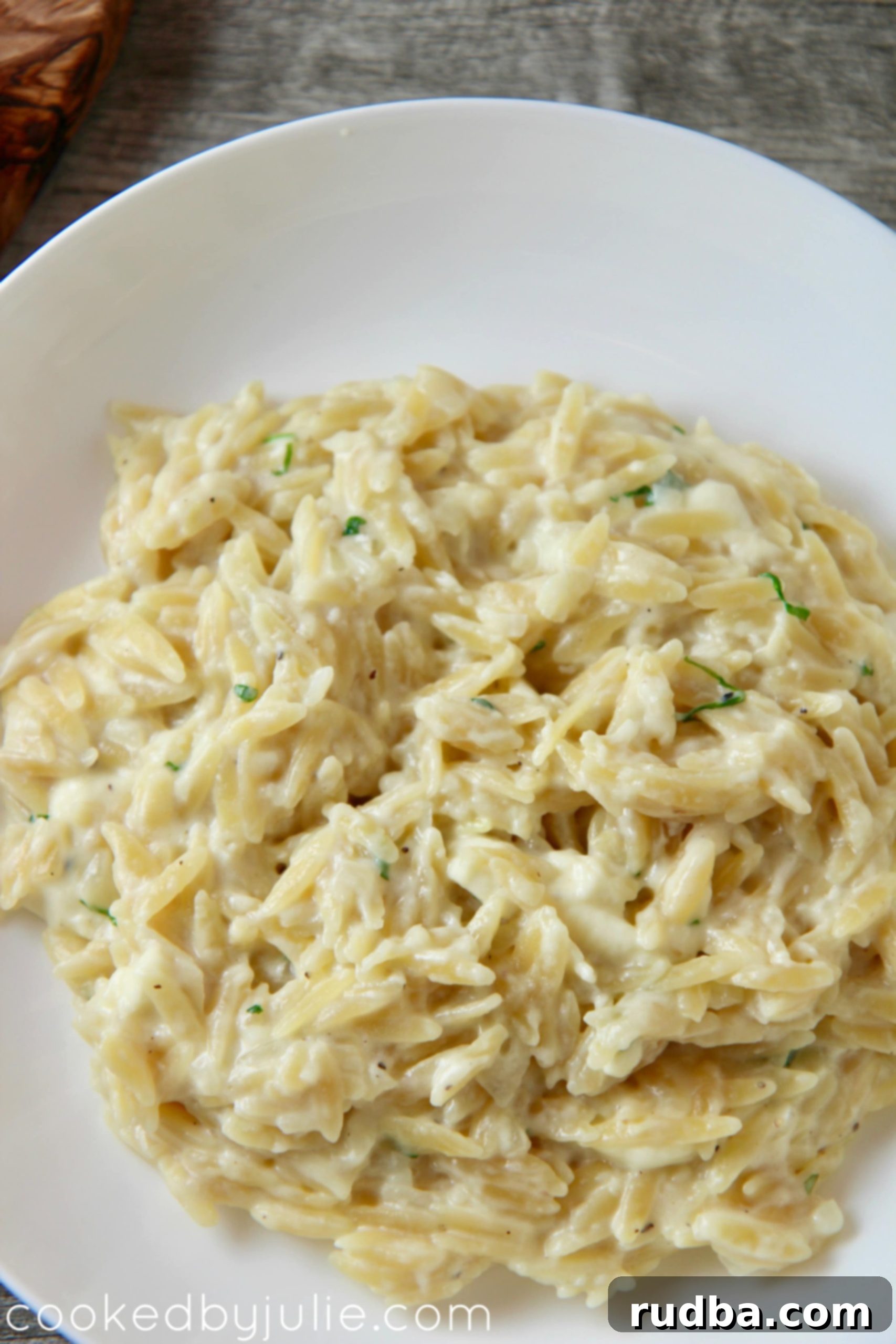 A close-up, appetizing view of a bowl of cheesy orzo, highlighting the steam, melted cheese, and creamy texture, making it look incredibly inviting.
