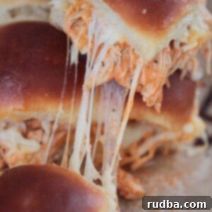 Close-up of buffalo chicken sliders on a plate, topped with melted cheese.