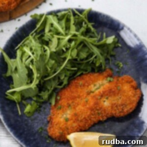 Crispy Golden Chicken Milanese 2 Crispy chicken Milanese with a lemon wedge and arugula on the side.