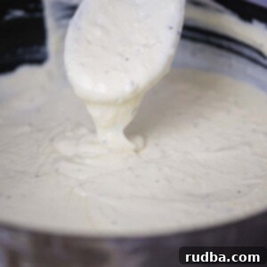 Creamy Homemade Triple Cheese Alfredo 2 three cheese alfredo sauce in a skillet with a wooden spoon.