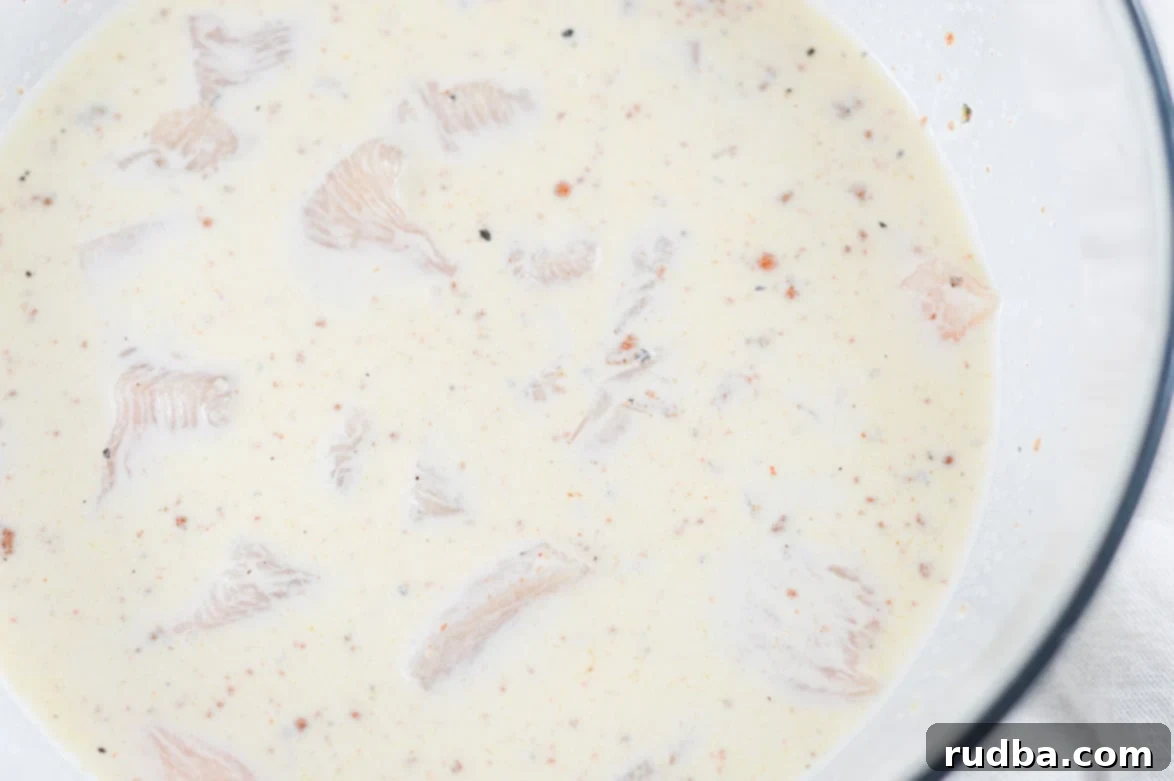 chicken coated in buttermilk in a large glass bowl 