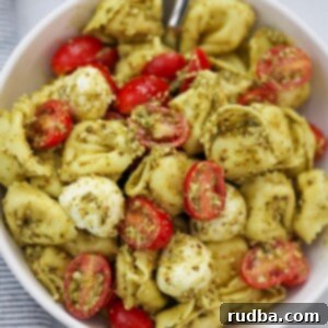 Vibrant Pesto Tortellini Salad 2 pesto tortellini salad in a bowl with a spoon.