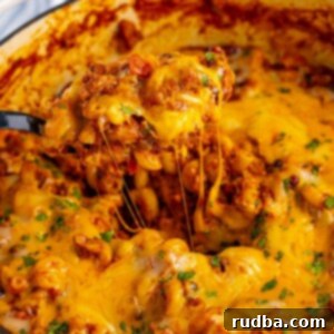 chili mac and cheese in a large pot with a spoon.