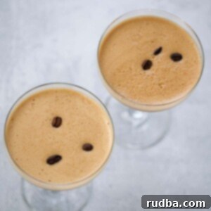 Espresso Kick Martini 2 Two espresso martinis with foamy tops and coffee beans.