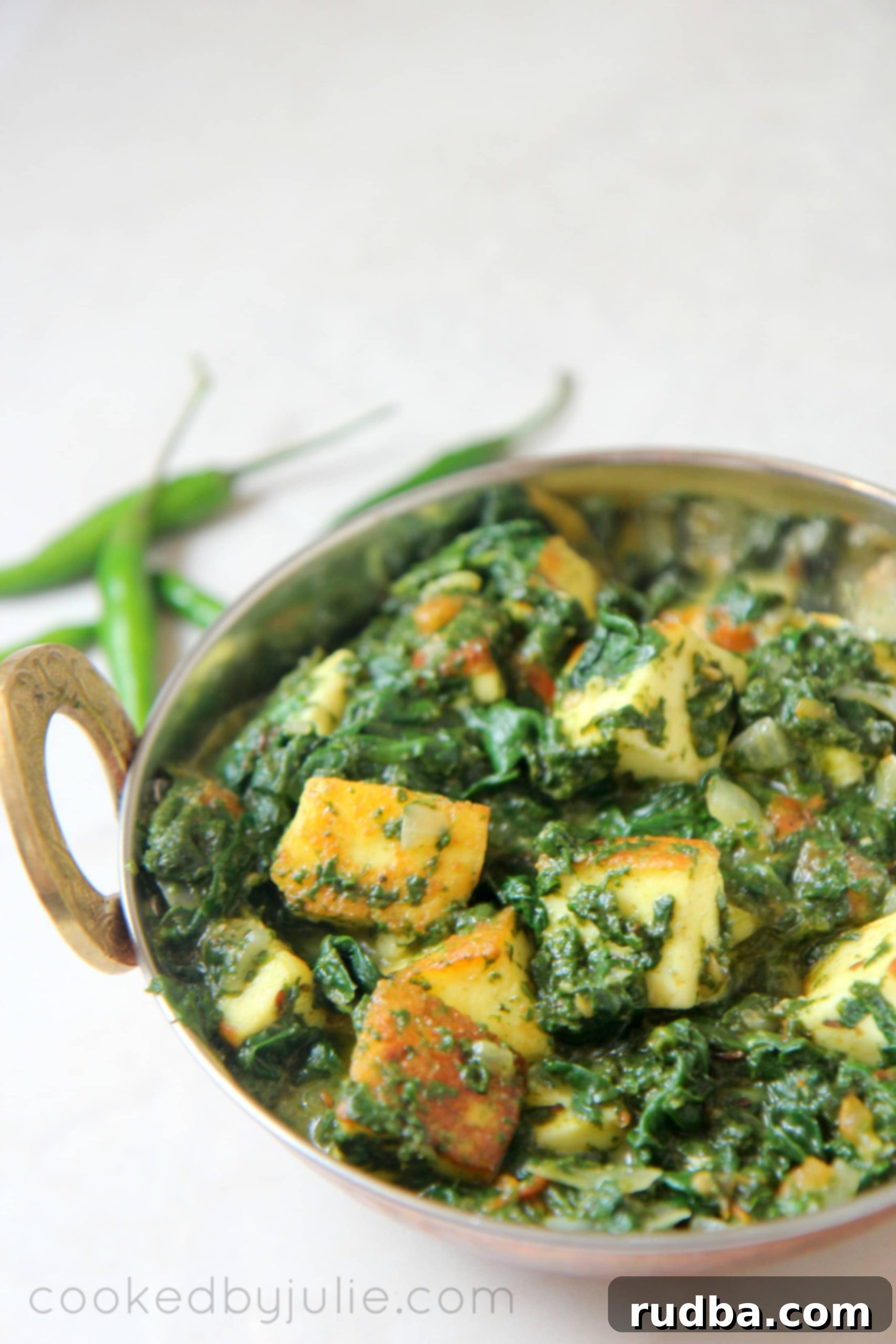 Saag paneer in a gold small dish with green chilies on the side