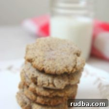 keto sugar cookies on a small white plate with a glass of milk in the background and a white and red towel.