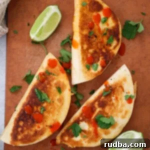 Gooey Buffalo Chicken Tacos 2 cheesy buffalo chicken tacos with lime wedges on the side.