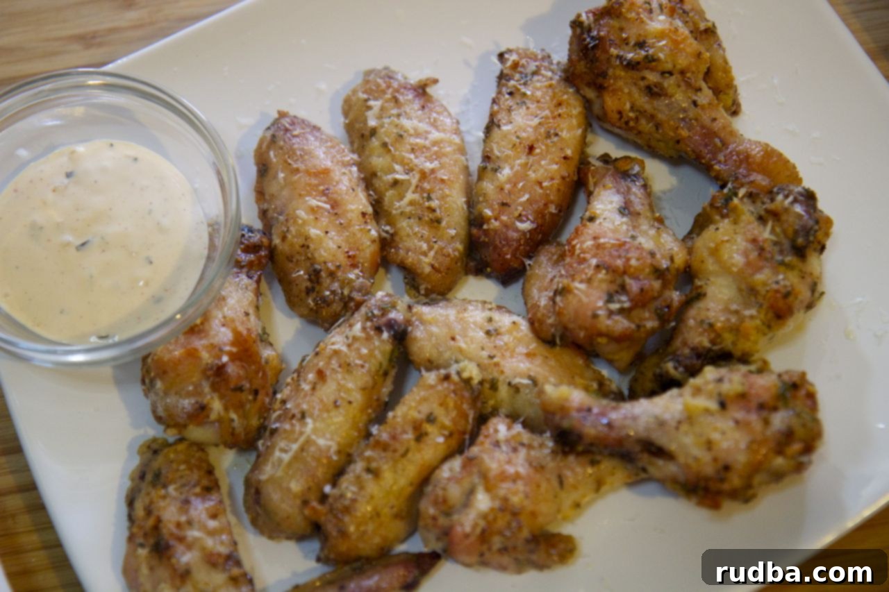 Up close view of golden-brown garlic Parmesan wings tossed in a rich sauce