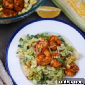 Spicy Blackened Shrimp Caesar 2 blackened shrimp caesar salad on a plate with a bowl of salad on the side.
