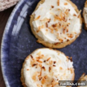 Two coconut cookies with cream cheese frosting on a blue plate.