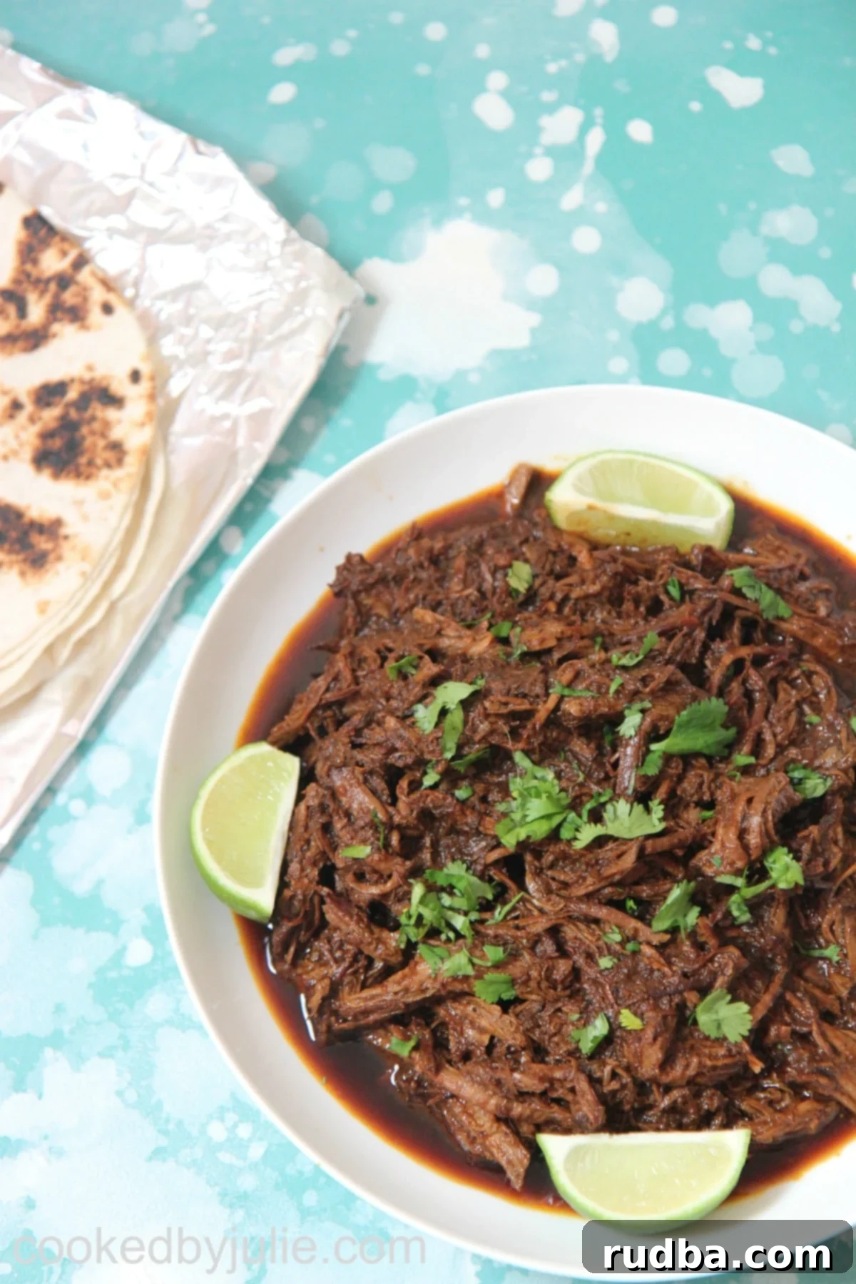 Beef barbacoa with lime wedges and cilantro