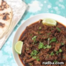 beef barbacoa with lime wedges and cilantro