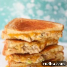 Golden Tuna Toastie 4 Close-up of a perfectly toasted tuna melt sandwich, showcasing its golden-brown bread and melted cheese oozing out, making it look incredibly appetizing.