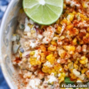 Mexican Street Corn Salad 2 elote corn salad in a bowl with a lime on the side.