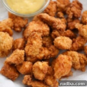 popcorn chicken on a plate with honey mustard on the side.