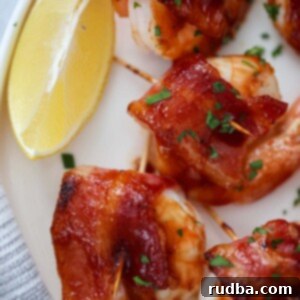 Crispy Bacon Shrimp Bites 2 bacon wrapped shrimp with a lemon wedge on the side.