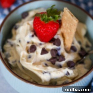 Creamy Chocolate Chip Cheesecake Dip 2 chocolate chip cheesecake dip in a bowl with a strawberry and graham cookie on top.