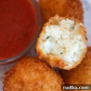 Three cheese arancini with marinara sauce on the side.