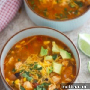 Two bowls of chicken noodle taco soup with a lime wedge on the side.